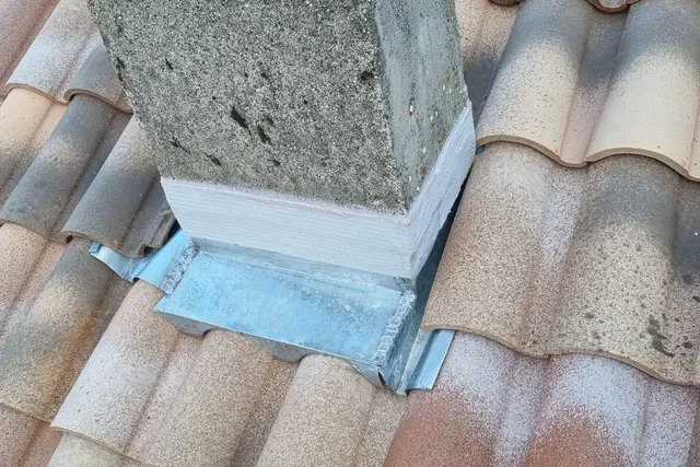 Solin en zinc au pied d'une souche de cheminée, sur une toiture en tuiles