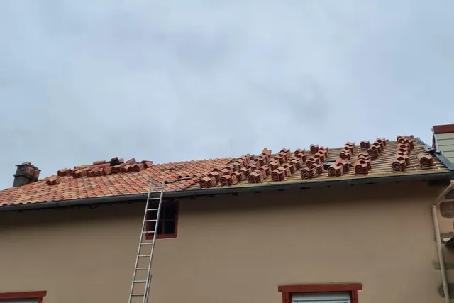 Maison dont la toiture est en cours de réfection, tuiles neuves en attente sur le toit et échelle en façade